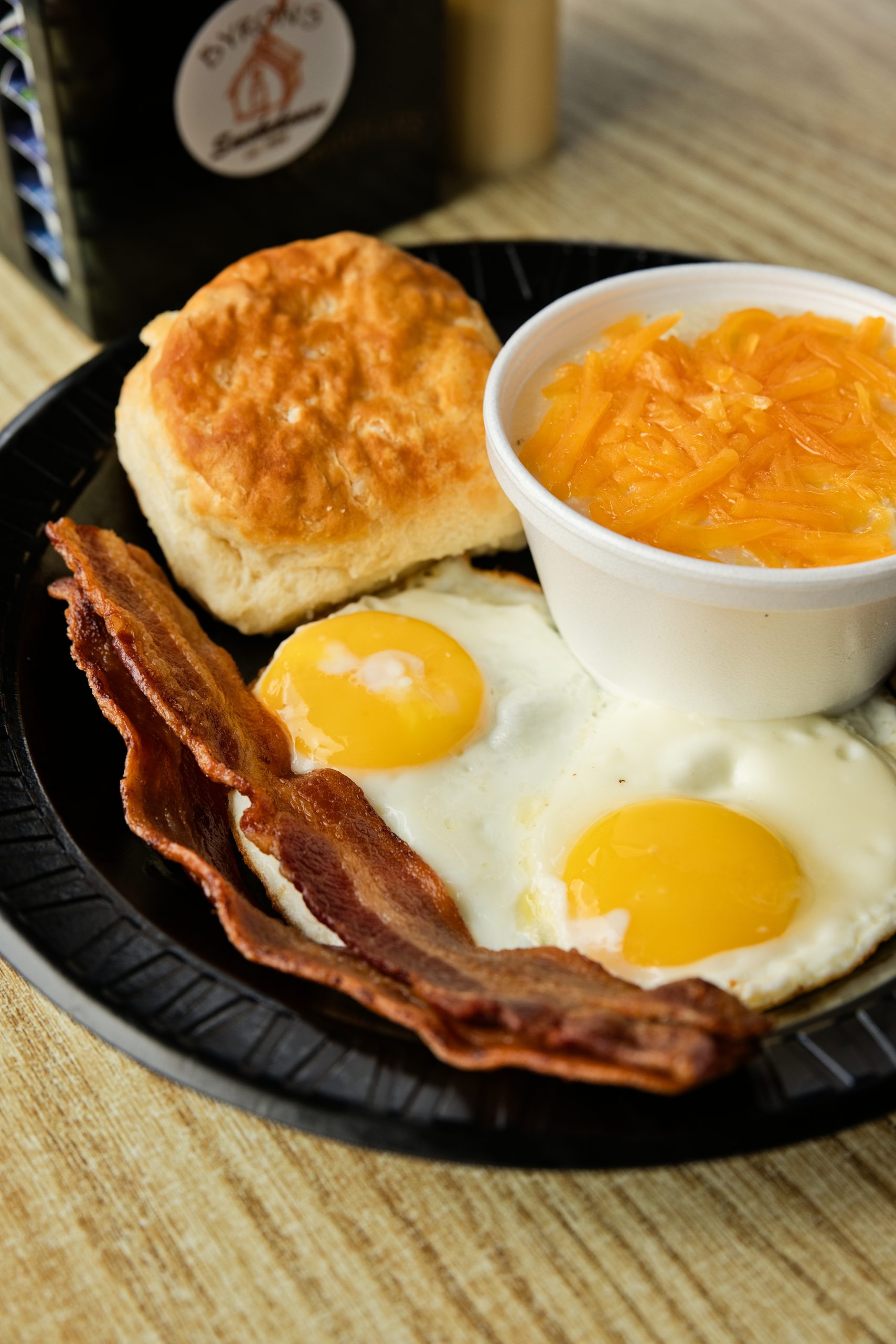Byron's breakfast plate with eggs, bacon, biscuit, and cheese grits